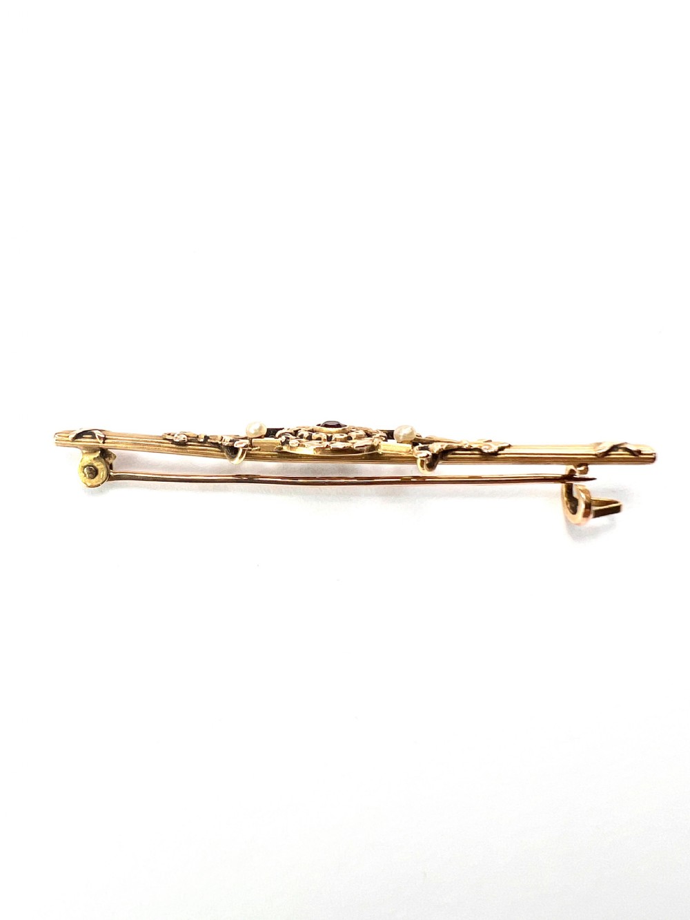 An antique 18-carat yellow gold bar brooch featuring a central circular motif with a round red garnet flanked by seed pearls and fluted bar details. View VII