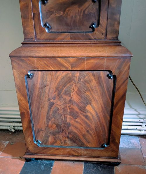 fig 2. A 19th-century flame mahogany longcase regulator clock with an arched pediment, round silvered dial, and panelled wooden trunk.