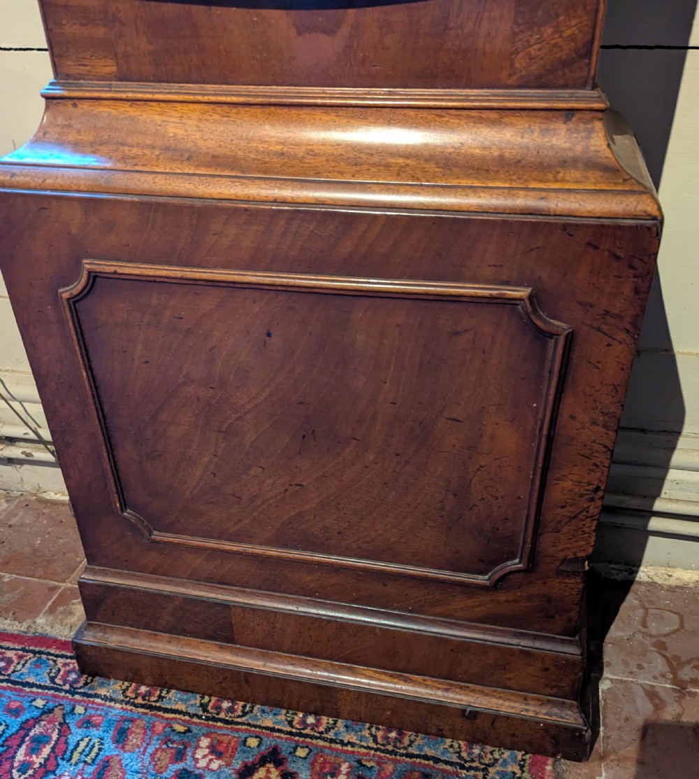An 18th-century mahogany longcase clock featuring brass eagle finials, an arched dial hood, and a flame mahogany trunk door. View V