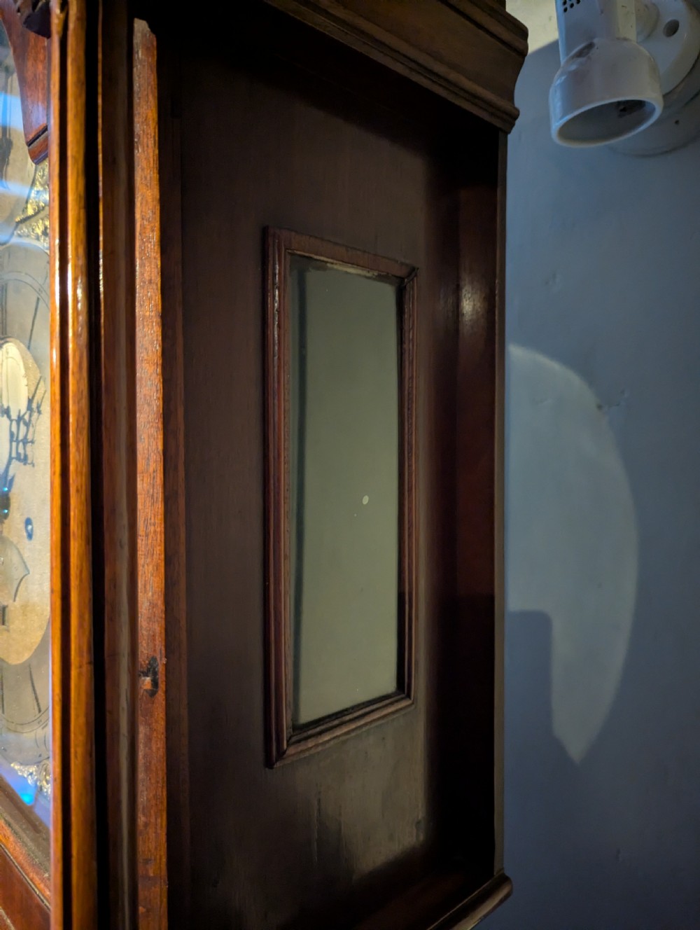 An 18th-century mahogany longcase clock featuring brass eagle finials, an arched dial hood, and a flame mahogany trunk door. View VII