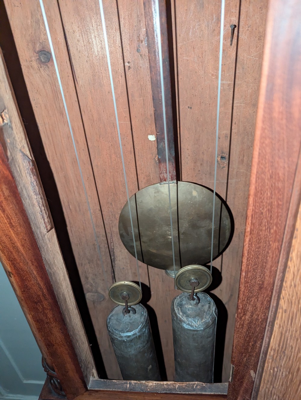 An early nineteenth-century flame mahogany domestic regulator longcase clock featuring an arched hood, circular dial with subsidiary dials, turned side columns, and an enclosed wooden base. View VI