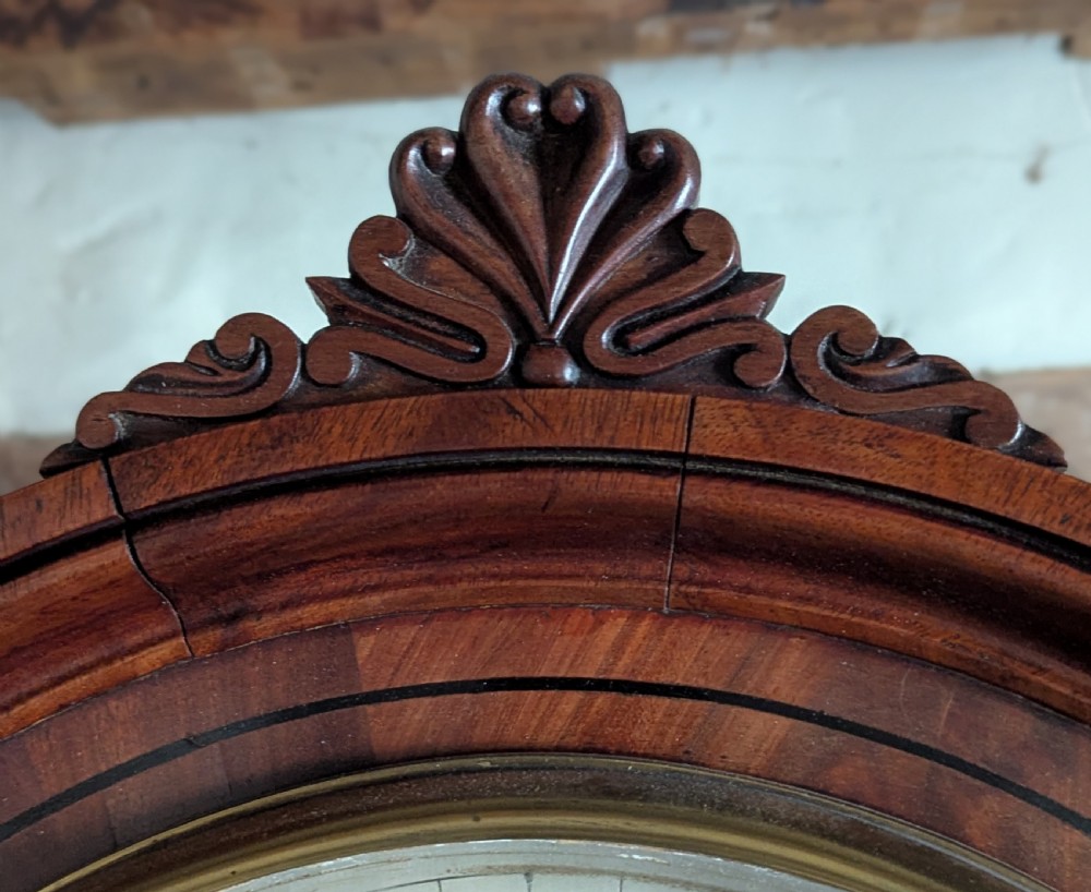 An early nineteenth-century flame mahogany domestic regulator longcase clock featuring an arched hood, circular dial with subsidiary dials, turned side columns, and an enclosed wooden base. View VII