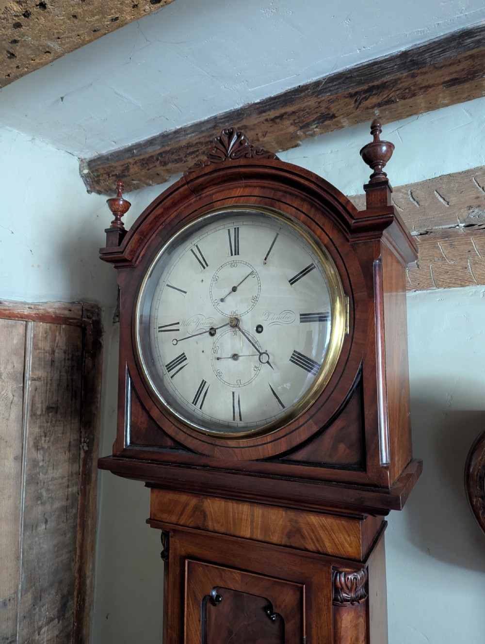 An early nineteenth-century flame mahogany domestic regulator longcase clock featuring an arched hood, circular dial with subsidiary dials, turned side columns, and an enclosed wooden base. View IX