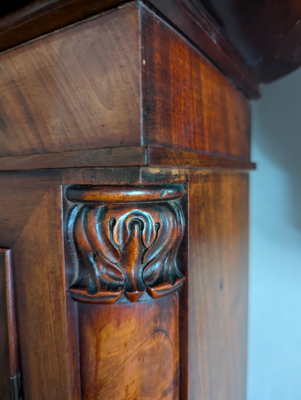 An early nineteenth-century flame mahogany domestic regulator longcase clock featuring an arched hood, circular dial with subsidiary dials, turned side columns, and an enclosed wooden base. View XIV