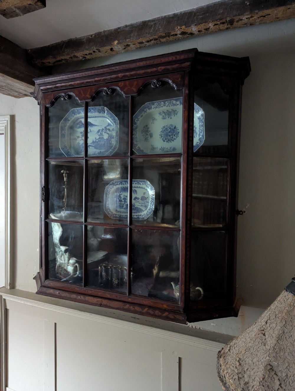 A 19th-century Dutch wall-mounted display cabinet crafted from dark wood with detailed floral marquetry inlay and multi-pane glazed doors. View II