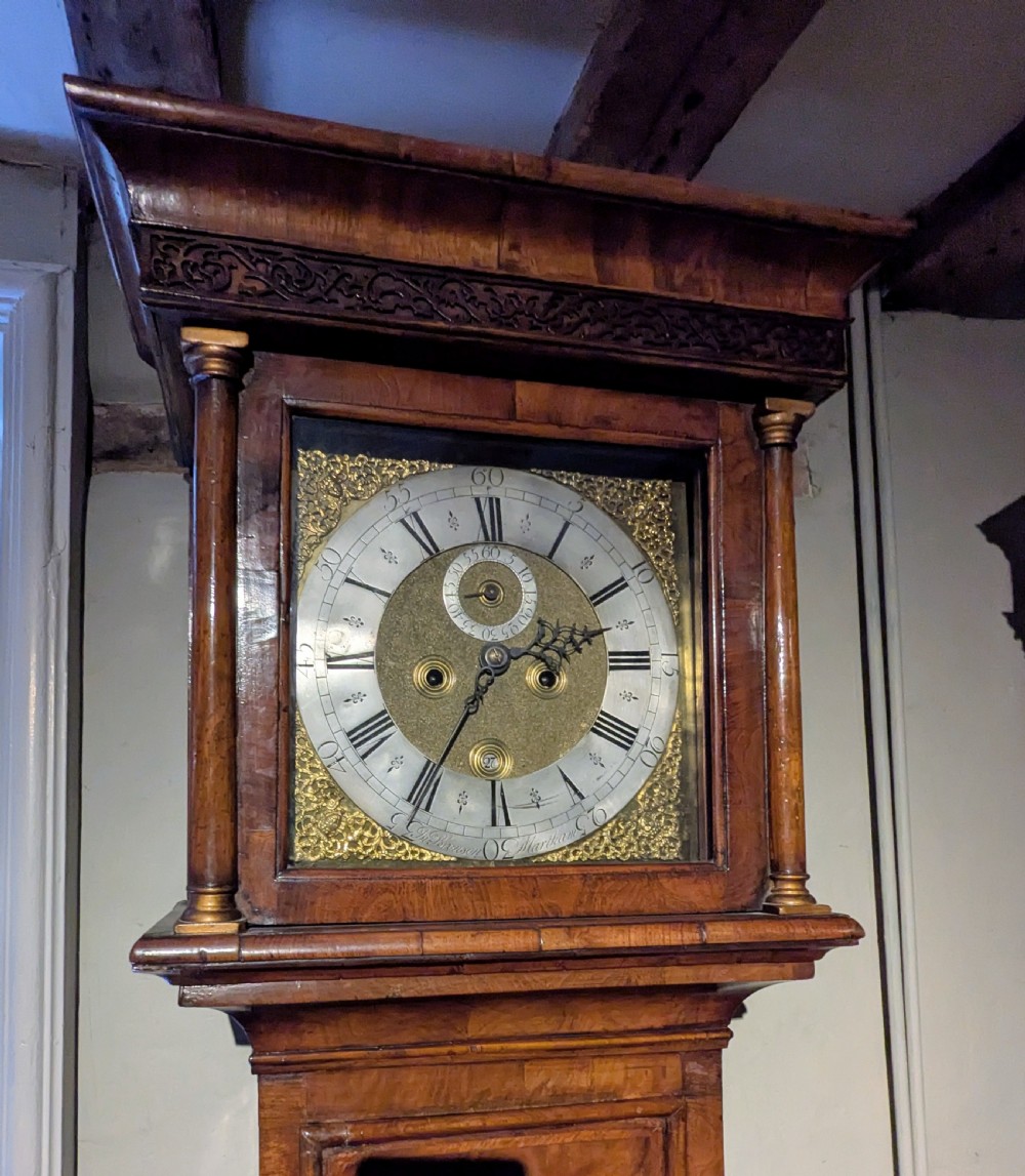 An 18th-century tall walnut longcase clock with a brass dial, turned hood columns, and a figured walnut veneered trunk. View VI