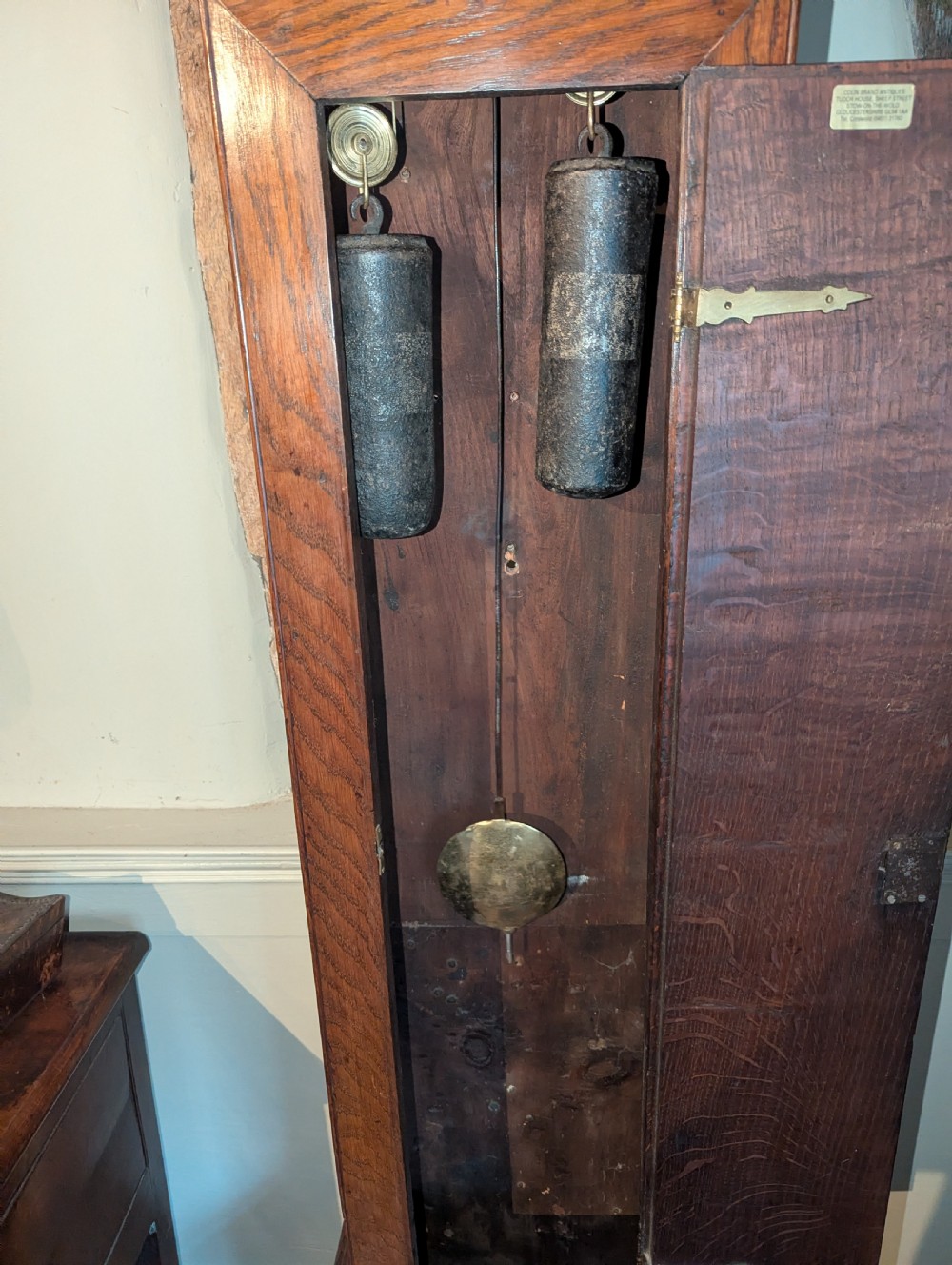 An 18th-century oak longcase clock featuring a square brass dial with spandrels, a moulded hood, and a slender wooden trunk. View II