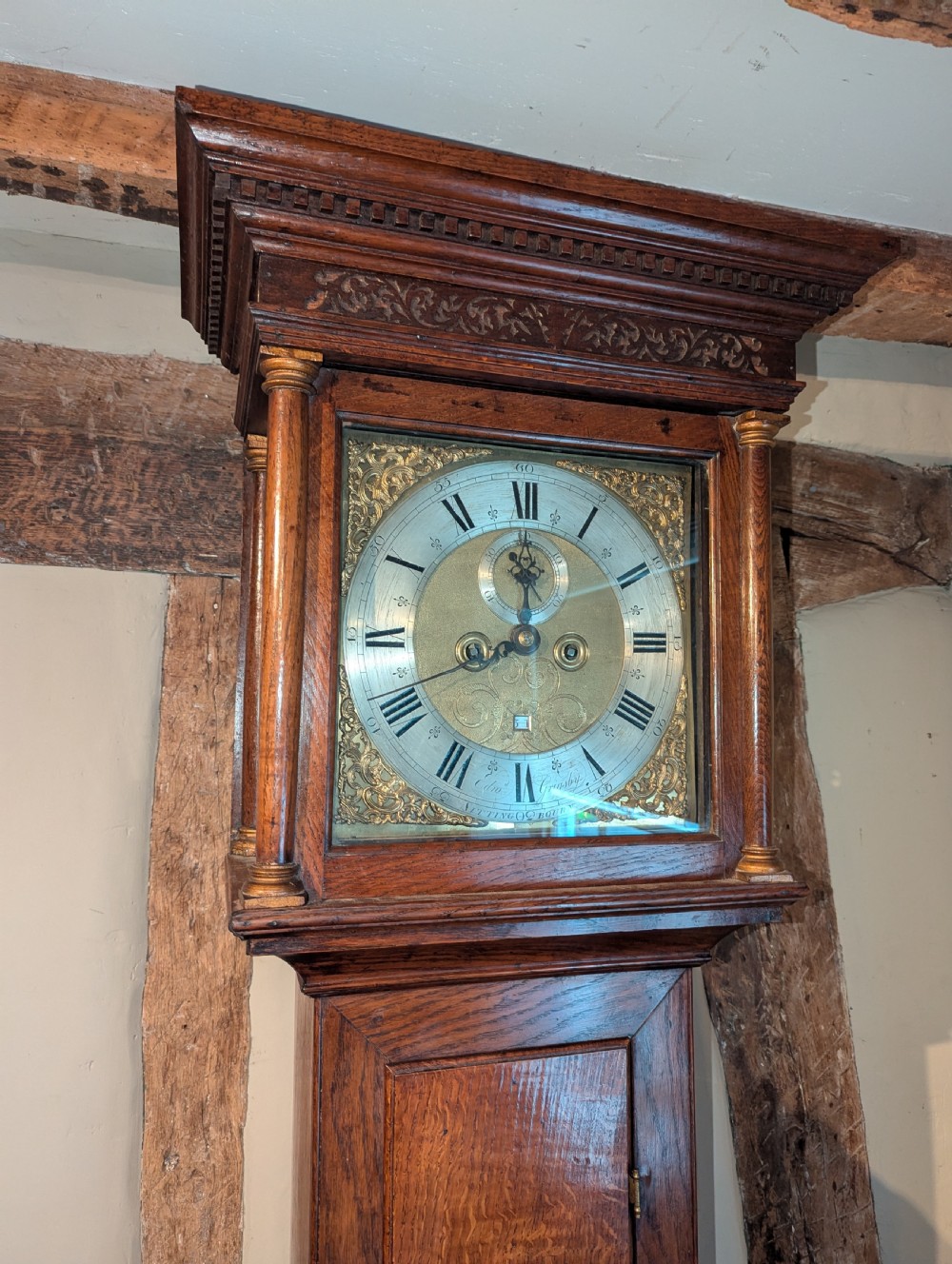 An 18th-century oak longcase clock featuring a square brass dial with spandrels, a moulded hood, and a slender wooden trunk. View III