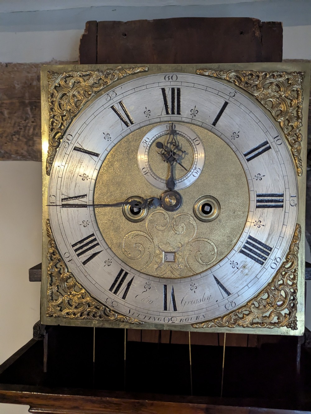 An 18th-century oak longcase clock featuring a square brass dial with spandrels, a moulded hood, and a slender wooden trunk. View VII