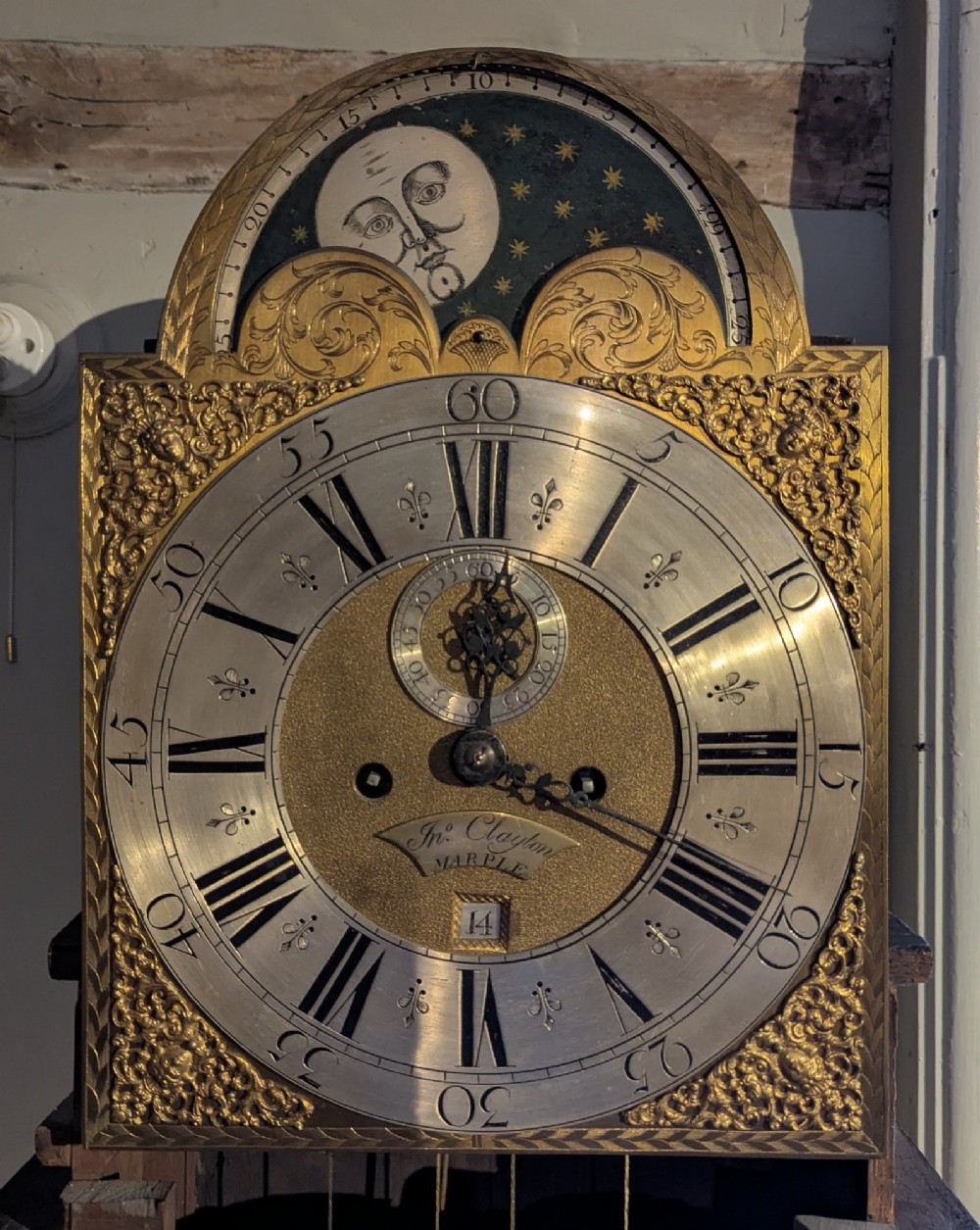 An eighteenth-century Georgian mahogany longcase clock with an arched hood, three brass eagle finials, and an engraved brass moon phase dial. View V