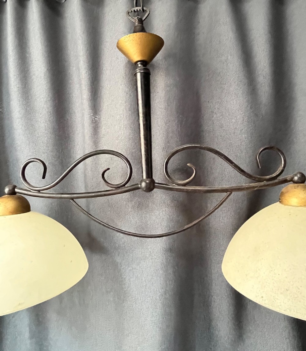 A 1940s French two-light downlighter featuring a black wrought-iron frame with scrollwork, brass accents, and two cream frosted glass dome shades. View VI