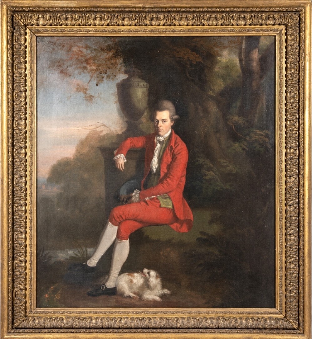 An eighteenth-century oil portrait of a gentleman in a red coat seated in a landscape next to a dog, presented in a carved giltwood frame.