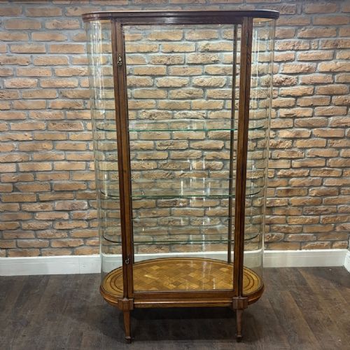 fig 1. A tall freestanding oak display cabinet featuring curved glass sides, three interior glass shelves, and a parquet oak base.