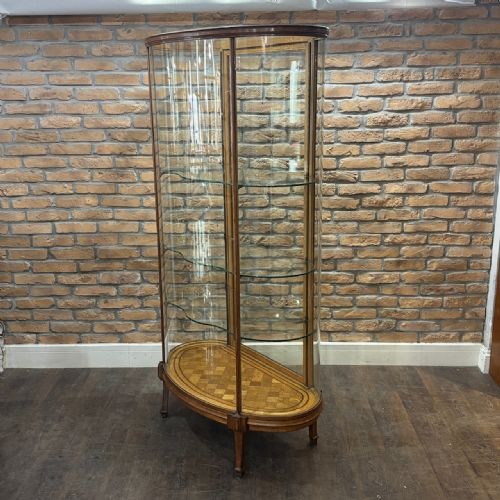 fig 2. A tall freestanding oak display cabinet featuring curved glass sides, three interior glass shelves, and a parquet oak base.