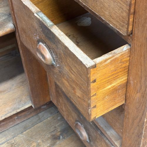 fig 3. An angled Edwardian oak commercial shop counter featuring recessed timber panels with carved decorative motifs and a heavy plinth base.