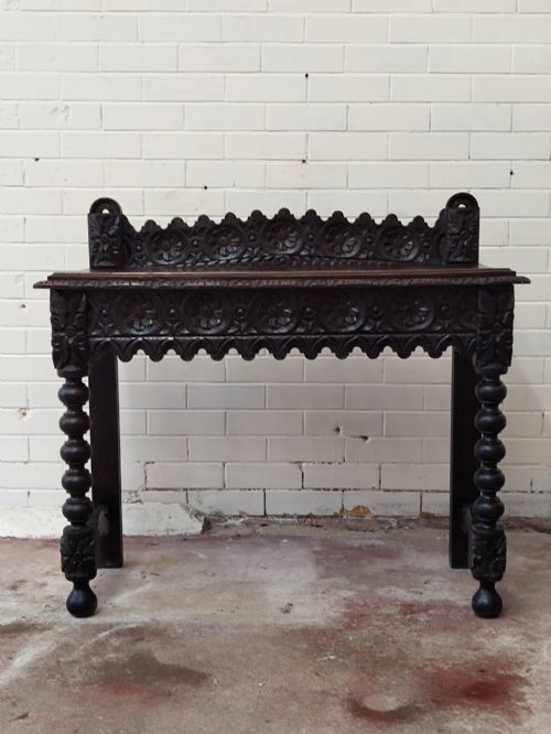 fig 1. Dark carved oak hall table featuring a carved floral gallery, relief apron, bobbin-turned front legs, and lower stretcher.