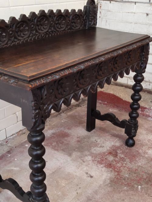 fig 4. Dark carved oak hall table featuring a carved floral gallery, relief apron, bobbin-turned front legs, and lower stretcher.