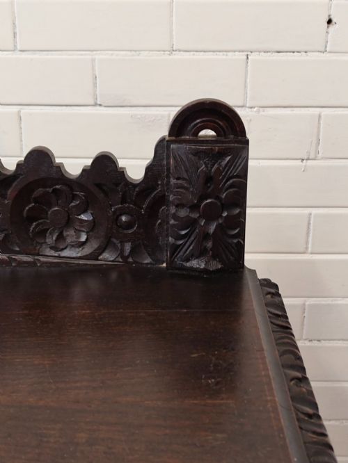 fig 5. Dark carved oak hall table featuring a carved floral gallery, relief apron, bobbin-turned front legs, and lower stretcher.