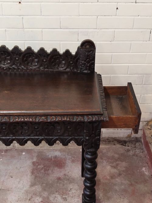 fig 8. Dark carved oak hall table featuring a carved floral gallery, relief apron, bobbin-turned front legs, and lower stretcher.