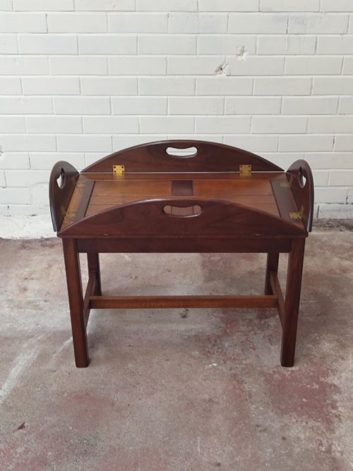 fig 1. An antique mahogany butlers tray with hinged folding sides and brass fittings resting on a rectangular wooden stand.