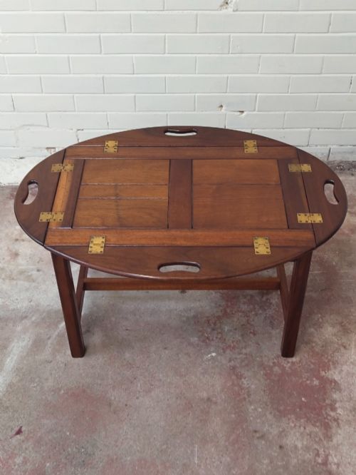 fig 3. An antique mahogany butlers tray with hinged folding sides and brass fittings resting on a rectangular wooden stand.