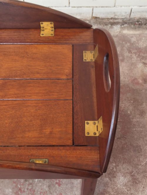 fig 4. An antique mahogany butlers tray with hinged folding sides and brass fittings resting on a rectangular wooden stand.