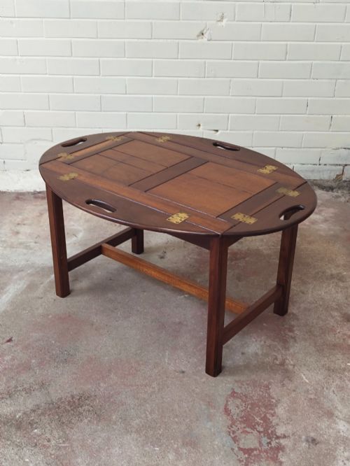 fig 7. An antique mahogany butlers tray with hinged folding sides and brass fittings resting on a rectangular wooden stand.