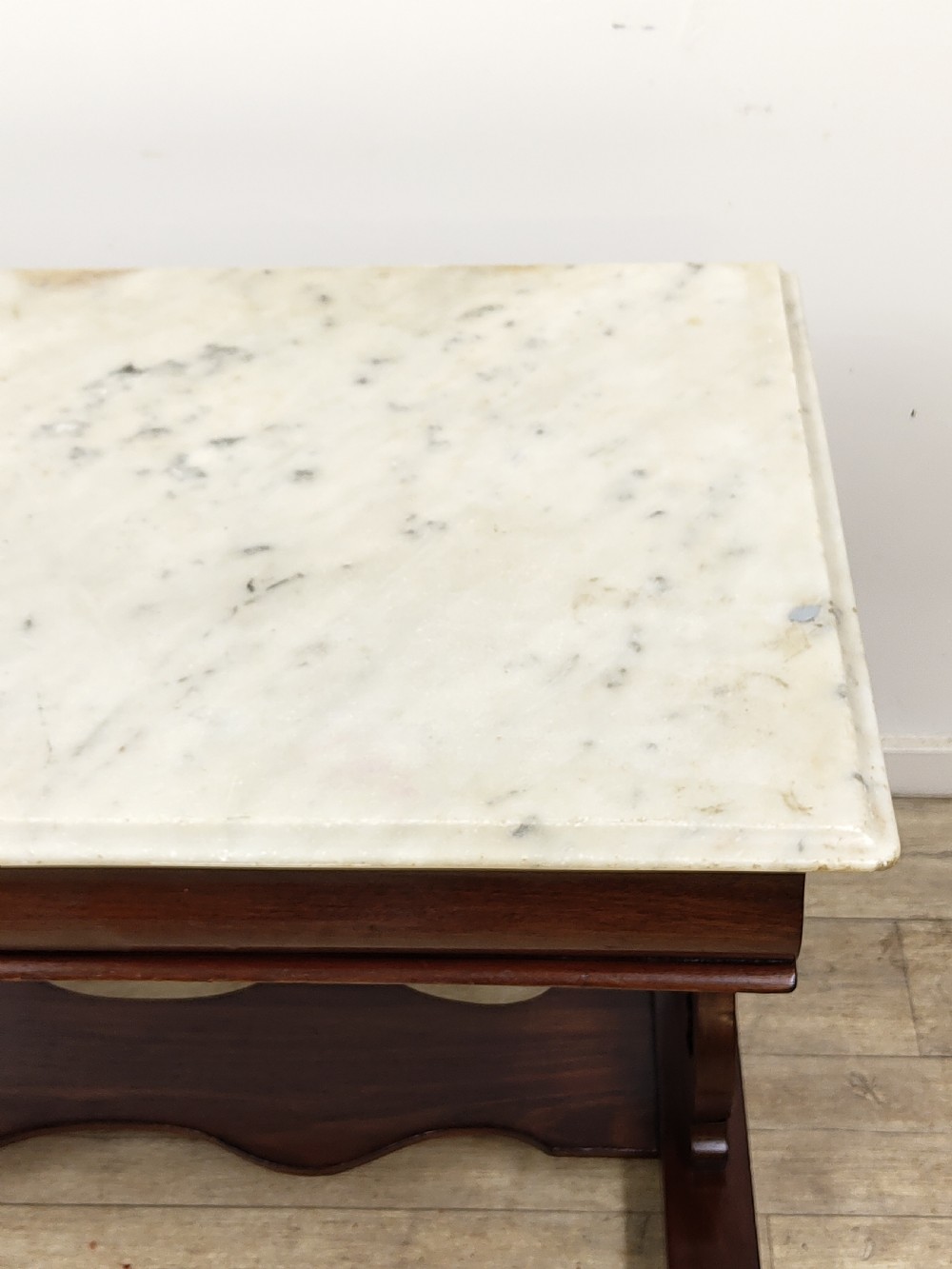 A Victorian mahogany washstand with a rectangular white marble top resting on twin pierced trestle supports linked by a shaped stretcher. View III