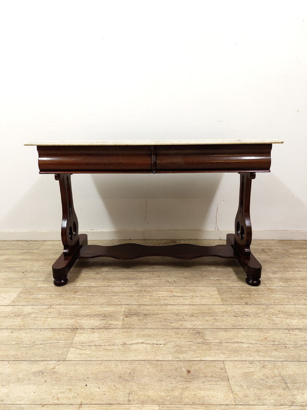 A Victorian mahogany washstand with a rectangular white marble top resting on twin pierced trestle supports linked by a shaped stretcher. View VII