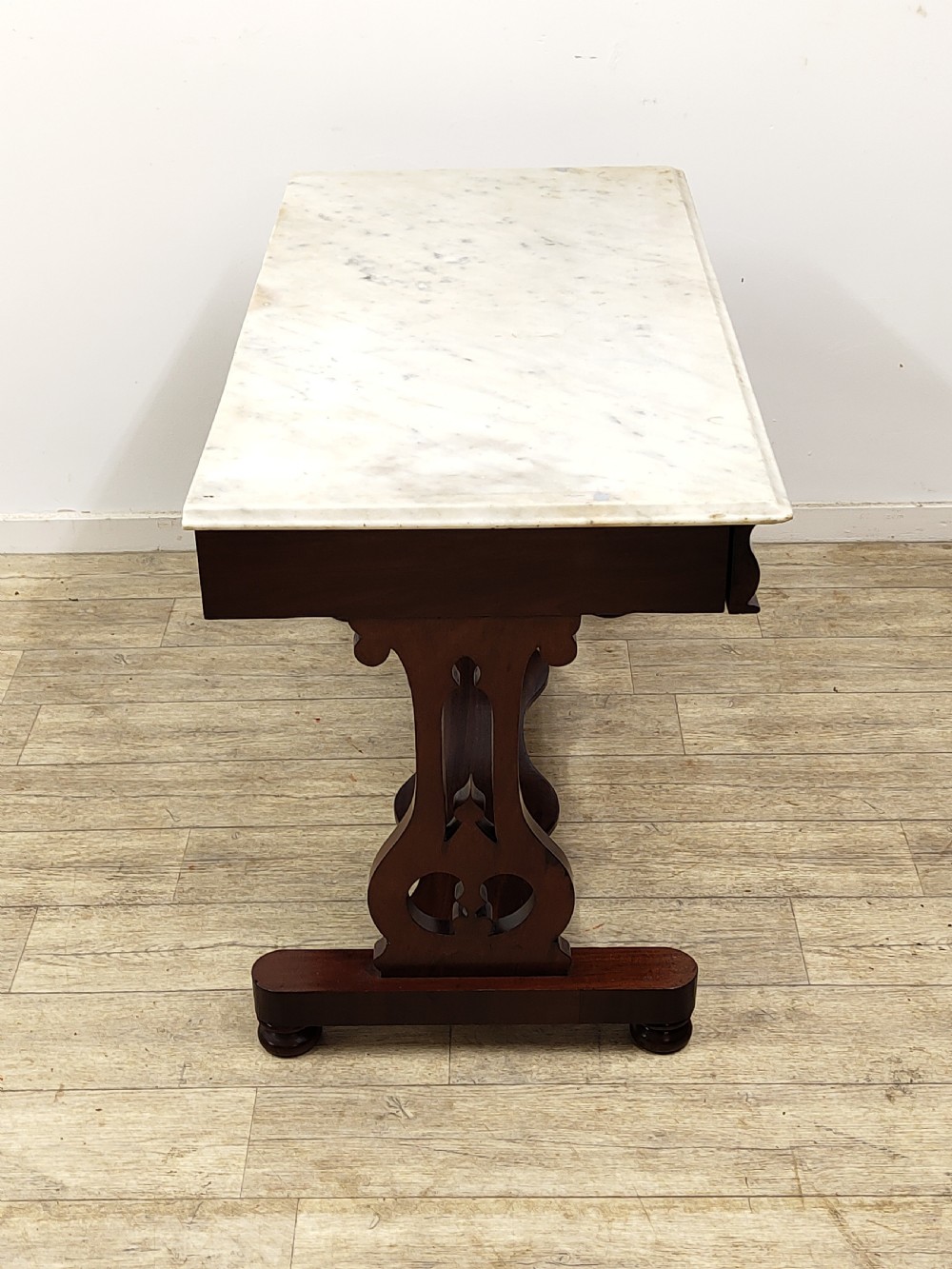A Victorian mahogany washstand with a rectangular white marble top resting on twin pierced trestle supports linked by a shaped stretcher. View IX