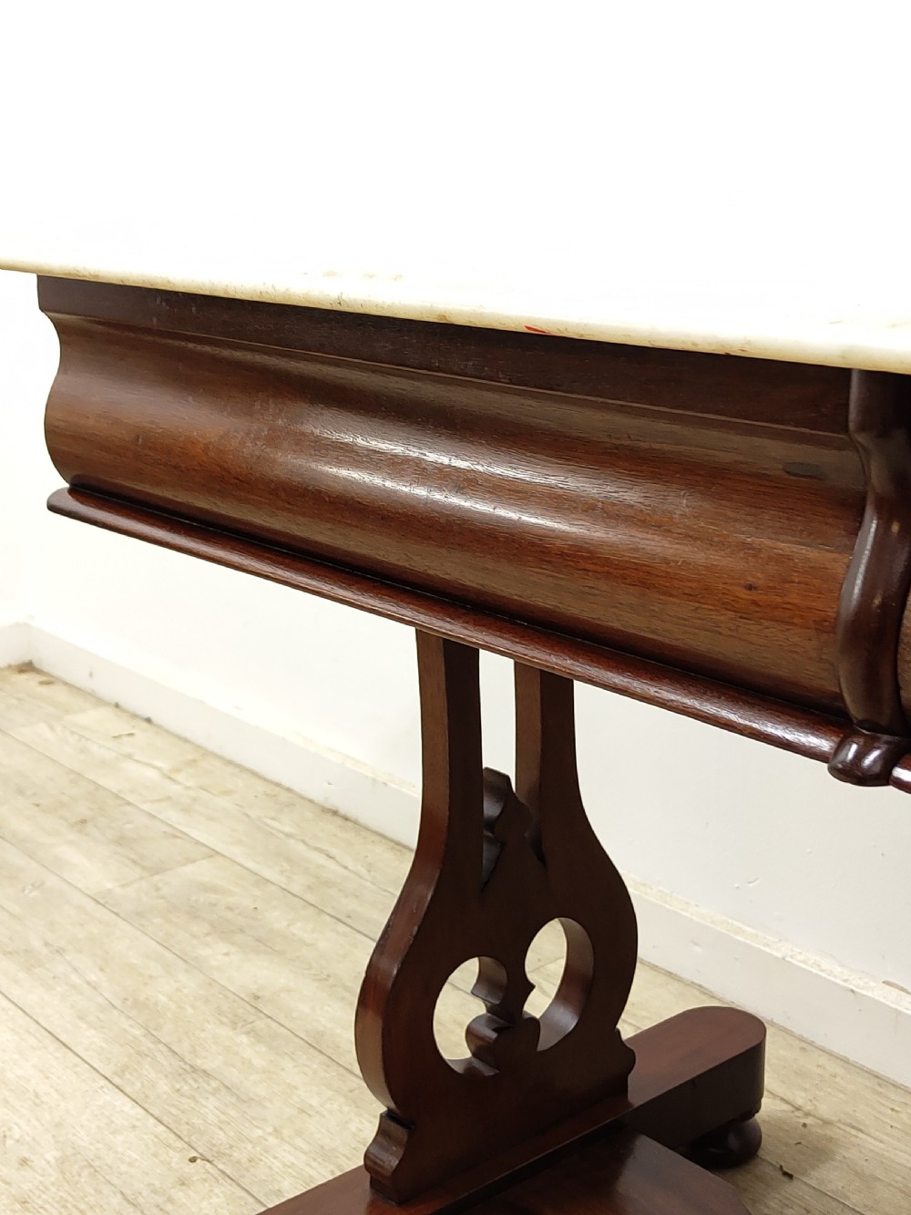 A Victorian mahogany washstand with a rectangular white marble top resting on twin pierced trestle supports linked by a shaped stretcher. View XII