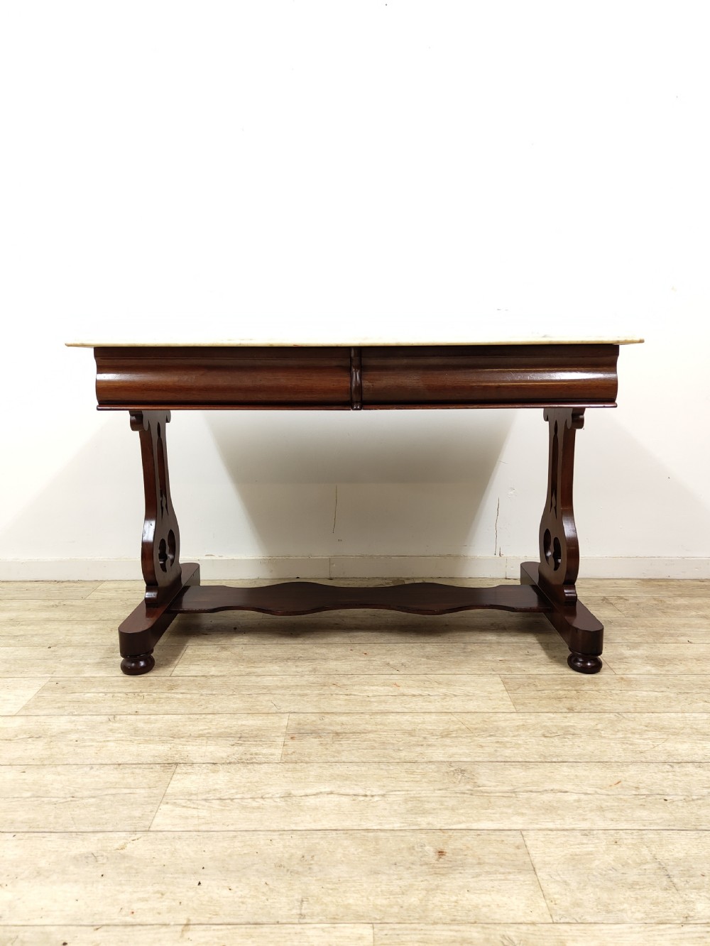 A Victorian mahogany washstand with a rectangular white marble top resting on twin pierced trestle supports linked by a shaped stretcher. View XVI