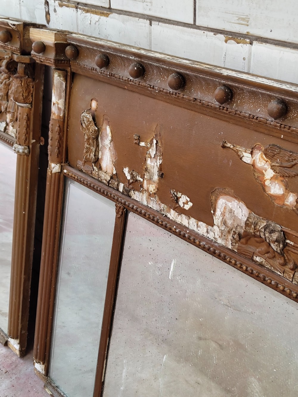 A pair of distressed Regency giltwood overmantel mirrors with classical relief friezes and tripartite mirror plates. View IX