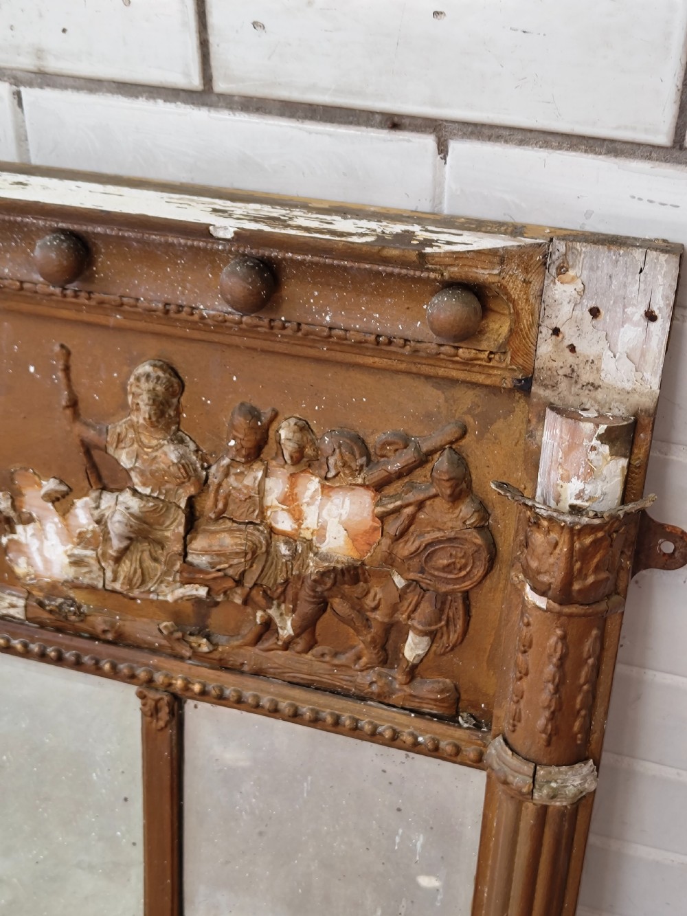 A pair of distressed Regency giltwood overmantel mirrors with classical relief friezes and tripartite mirror plates. View III