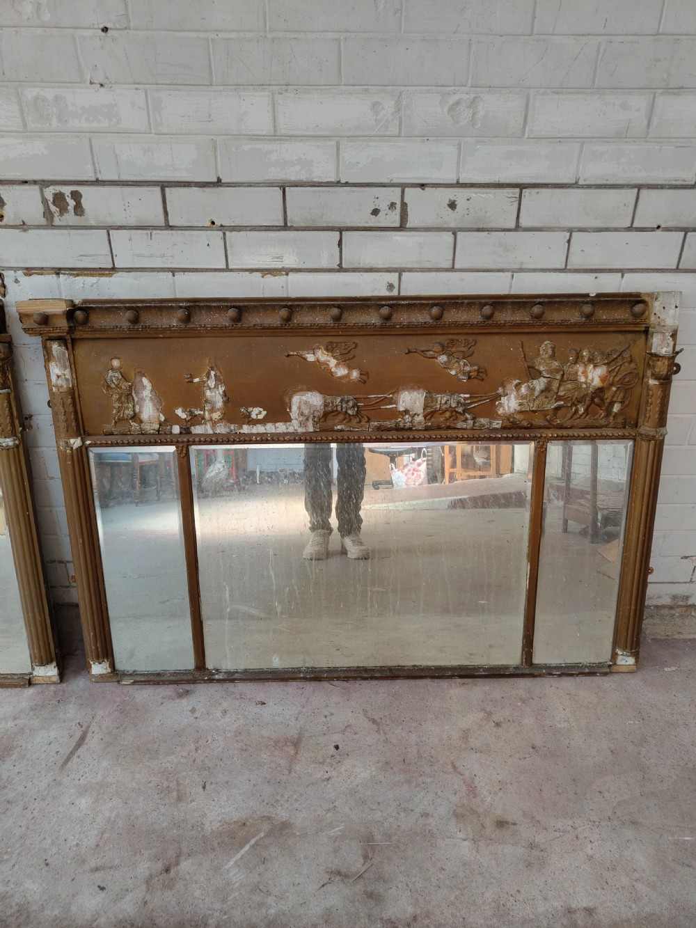 A pair of distressed Regency giltwood overmantel mirrors with classical relief friezes and tripartite mirror plates. View IV