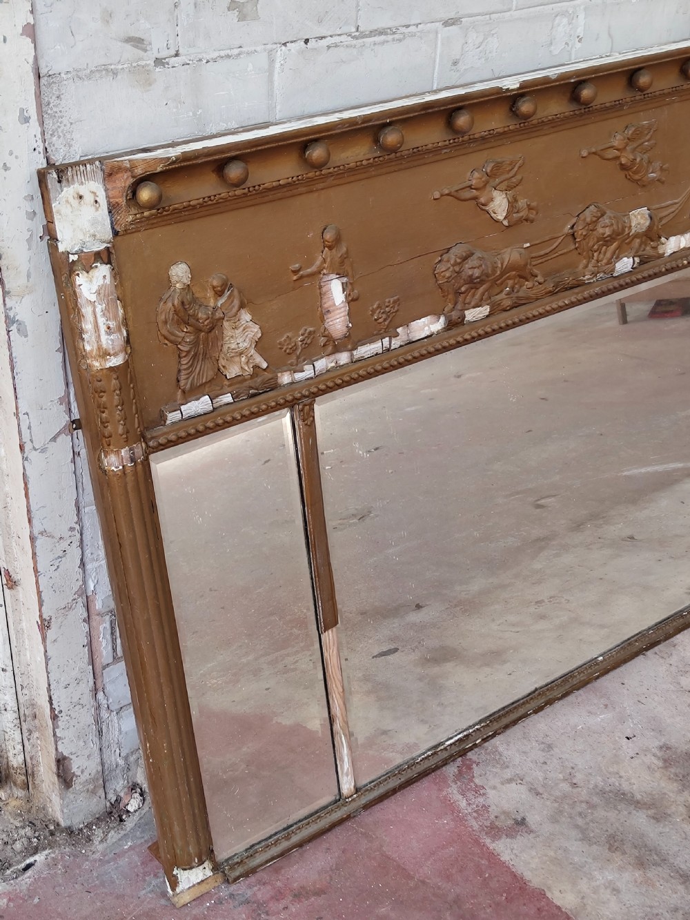 A pair of distressed Regency giltwood overmantel mirrors with classical relief friezes and tripartite mirror plates. View V
