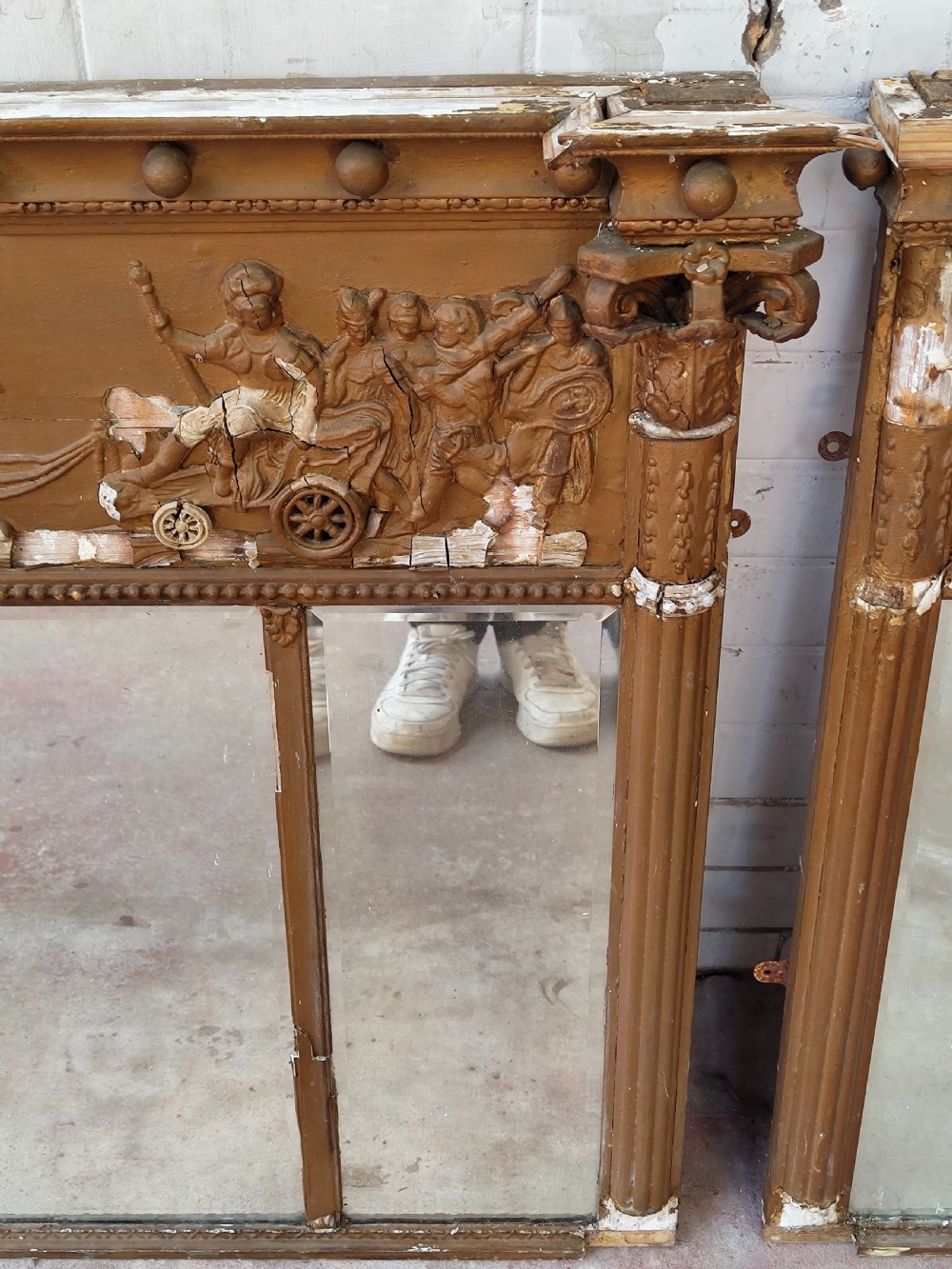 A pair of distressed Regency giltwood overmantel mirrors with classical relief friezes and tripartite mirror plates. View VI