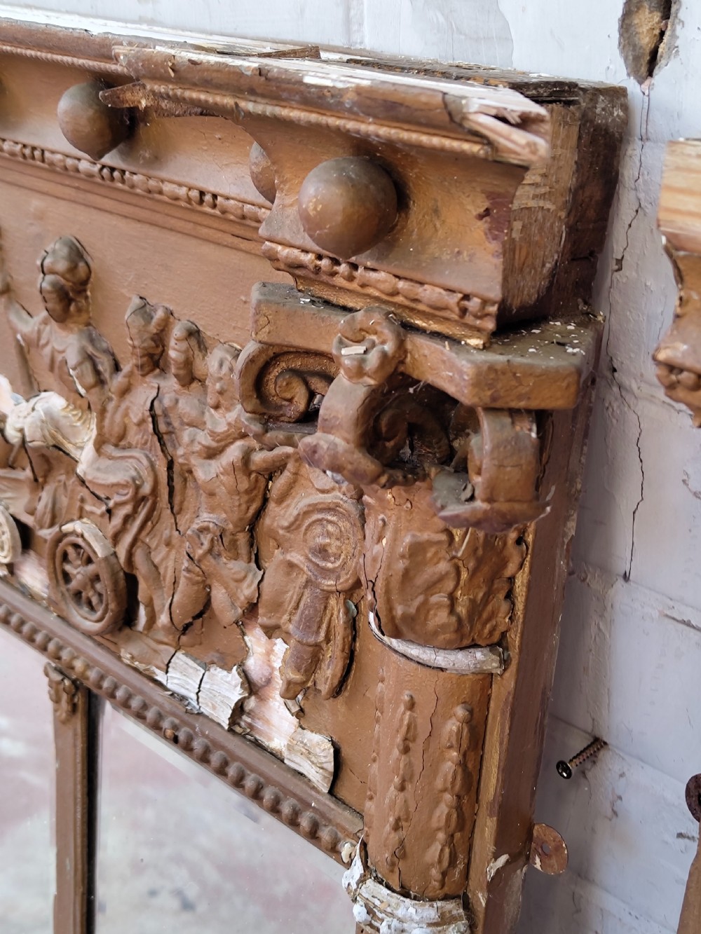 A pair of distressed Regency giltwood overmantel mirrors with classical relief friezes and tripartite mirror plates. View VII