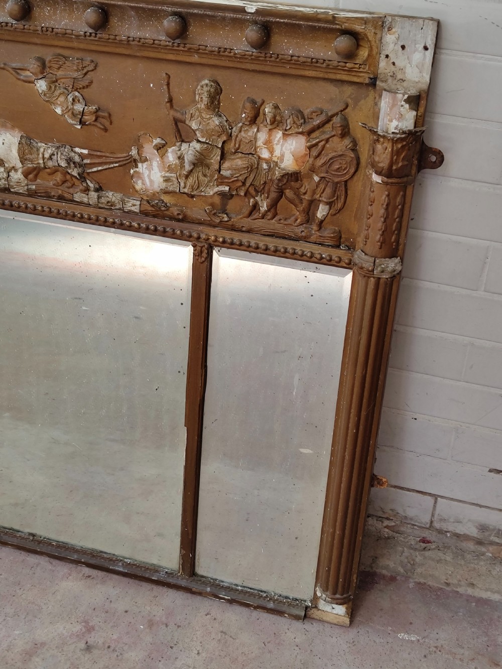 A pair of distressed Regency giltwood overmantel mirrors with classical relief friezes and tripartite mirror plates. View VIII