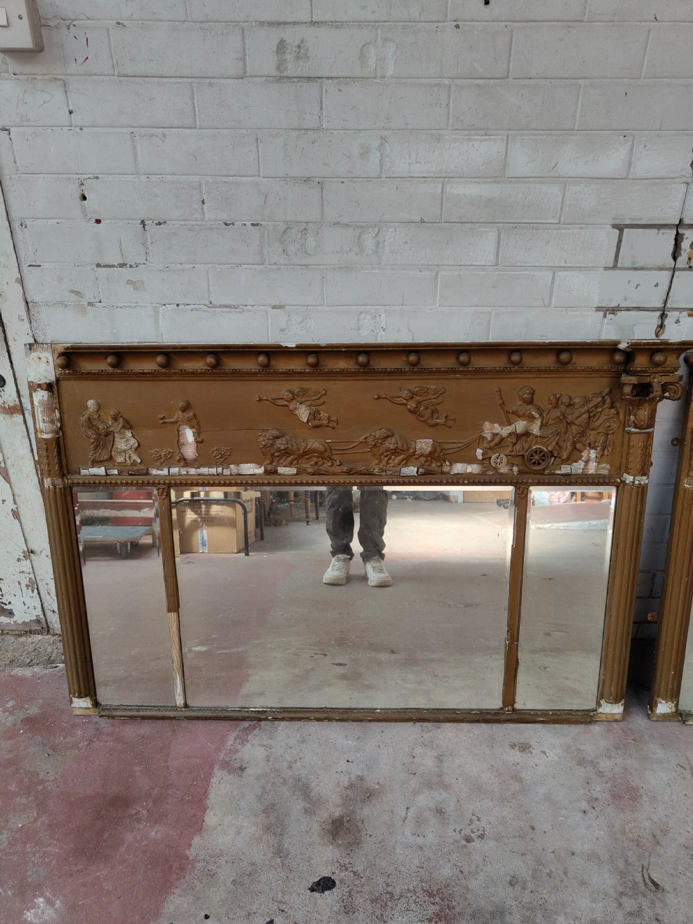 A pair of distressed Regency giltwood overmantel mirrors with classical relief friezes and tripartite mirror plates. View X