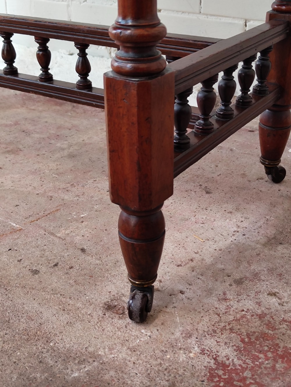 A solid walnut rectangular centre table featuring turned legs, a spindle-galleried lower stretcher, and brass castors. View VIII