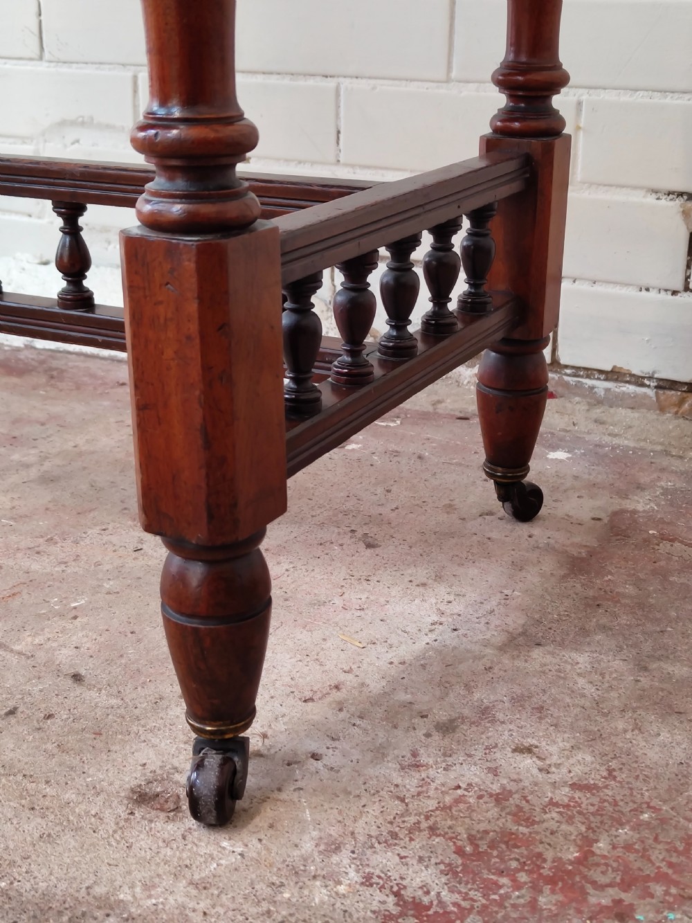 A solid walnut rectangular centre table featuring turned legs, a spindle-galleried lower stretcher, and brass castors. View II