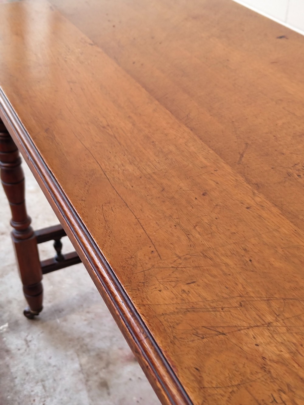 A solid walnut rectangular centre table featuring turned legs, a spindle-galleried lower stretcher, and brass castors. View III