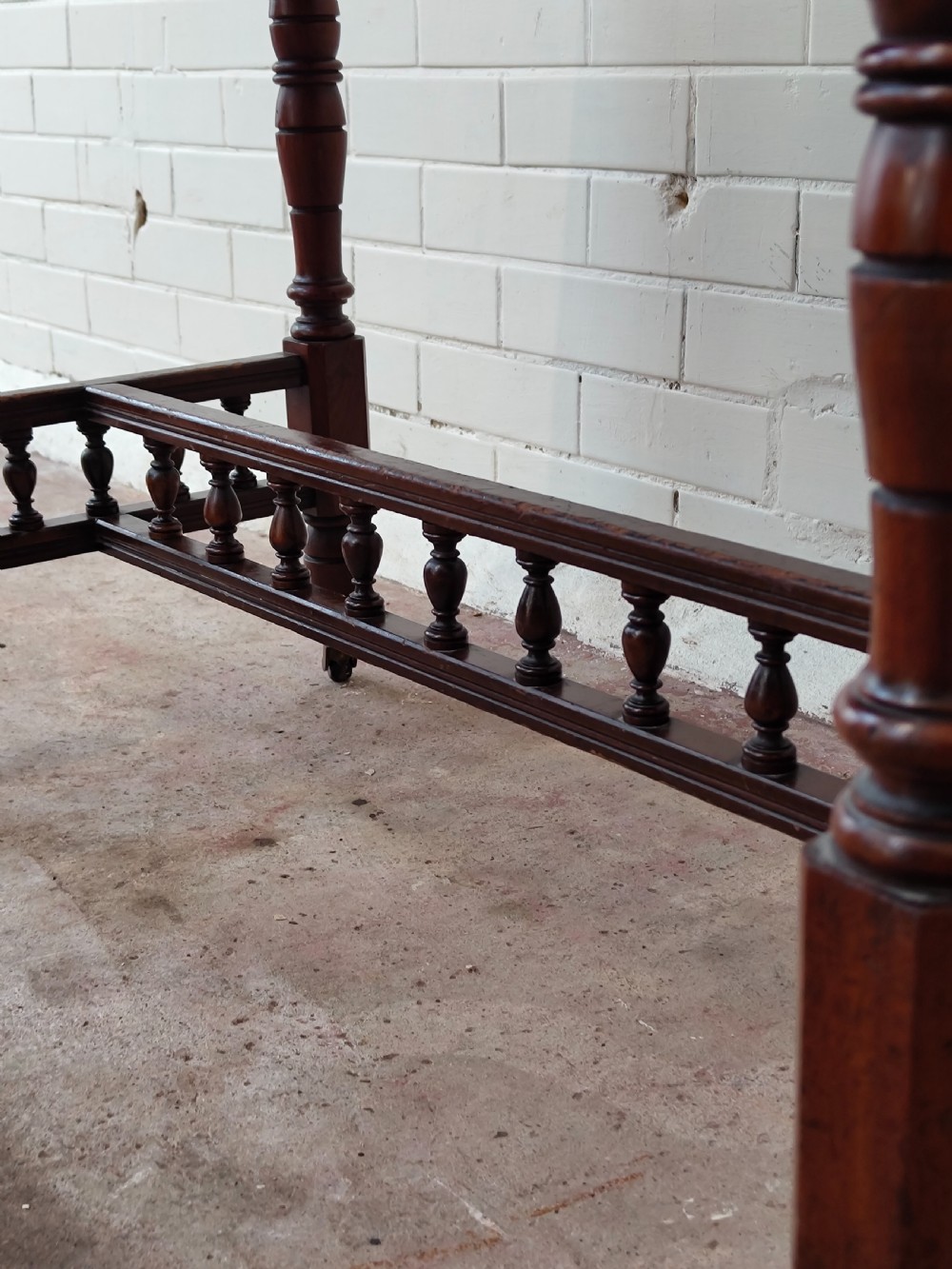 A solid walnut rectangular centre table featuring turned legs, a spindle-galleried lower stretcher, and brass castors. View IX
