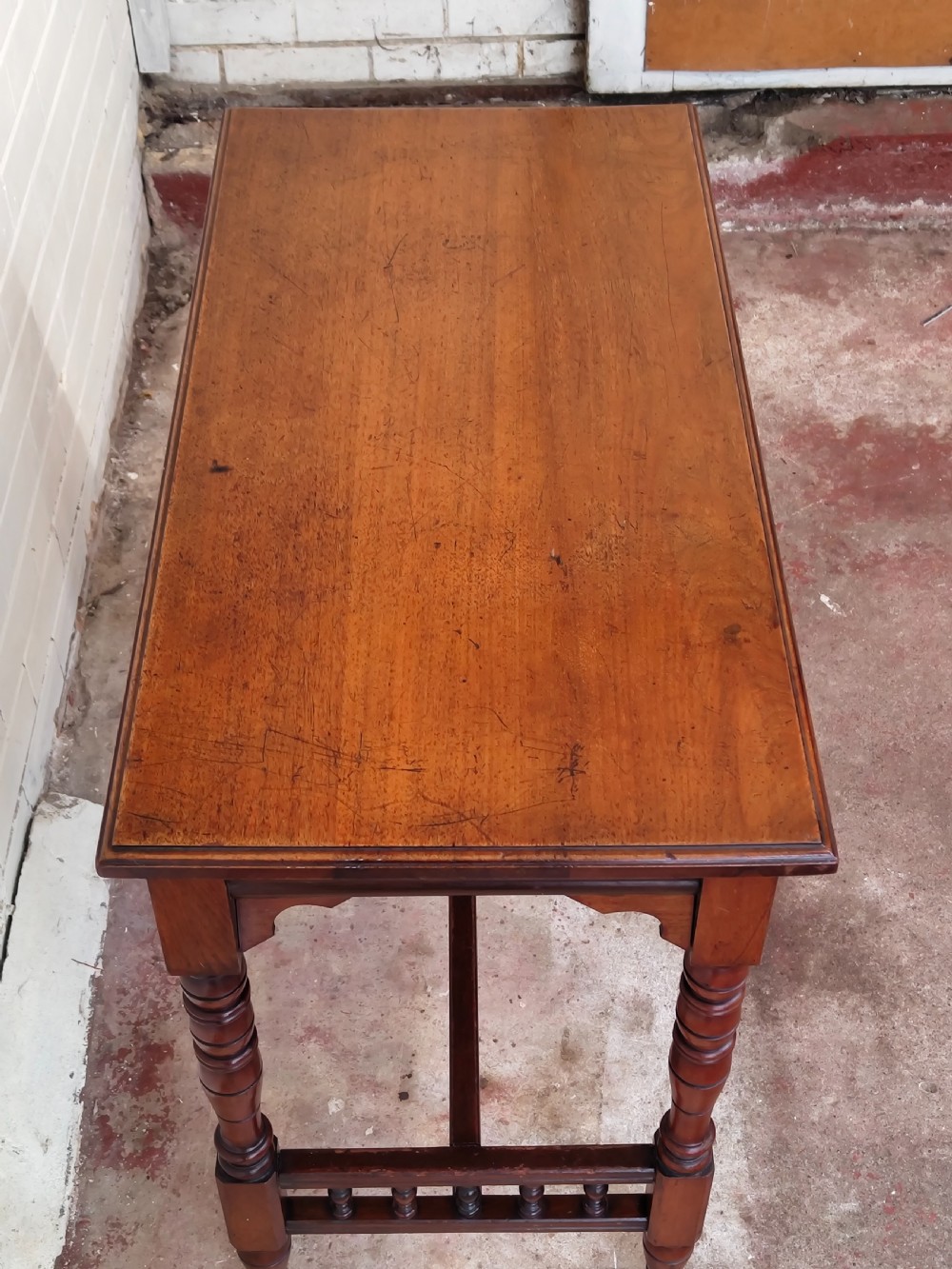 A solid walnut rectangular centre table featuring turned legs, a spindle-galleried lower stretcher, and brass castors. View XII