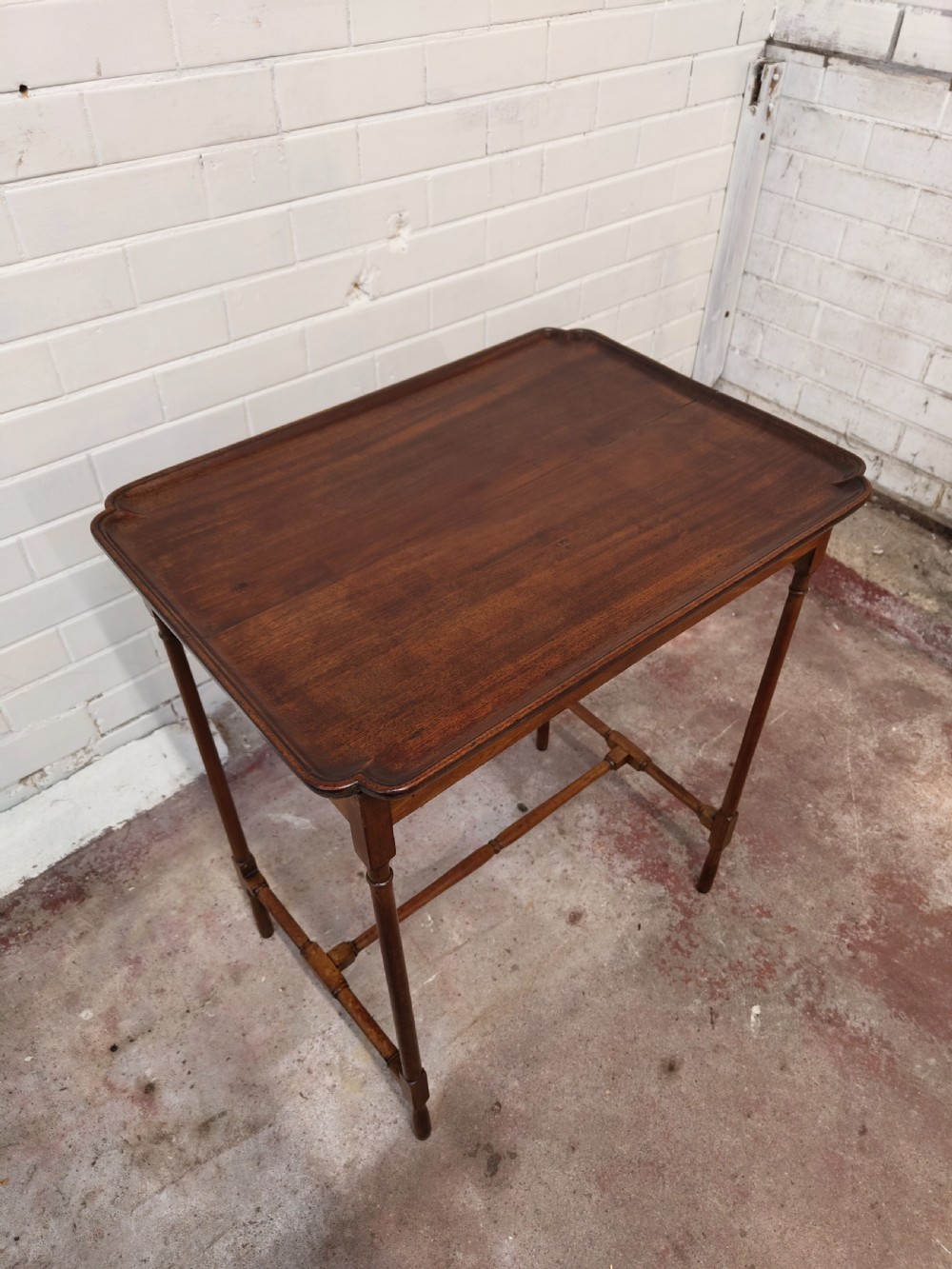 A tall Edwardian mahogany occasional table featuring a tray top with raised edges and slender spider legs connected by lower stretchers. View III