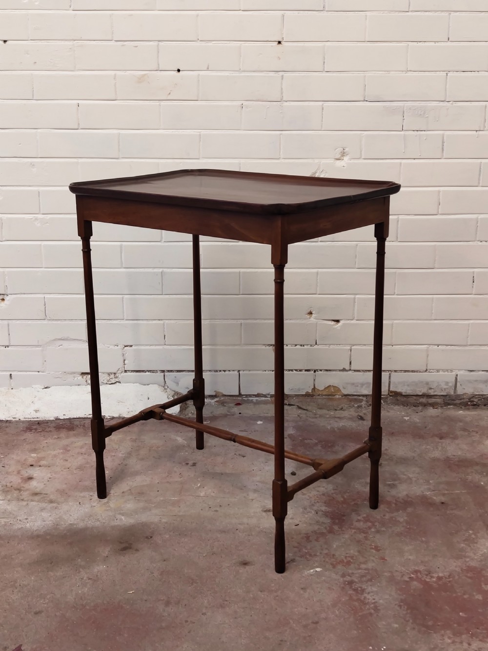 A tall Edwardian mahogany occasional table featuring a tray top with raised edges and slender spider legs connected by lower stretchers. View VI