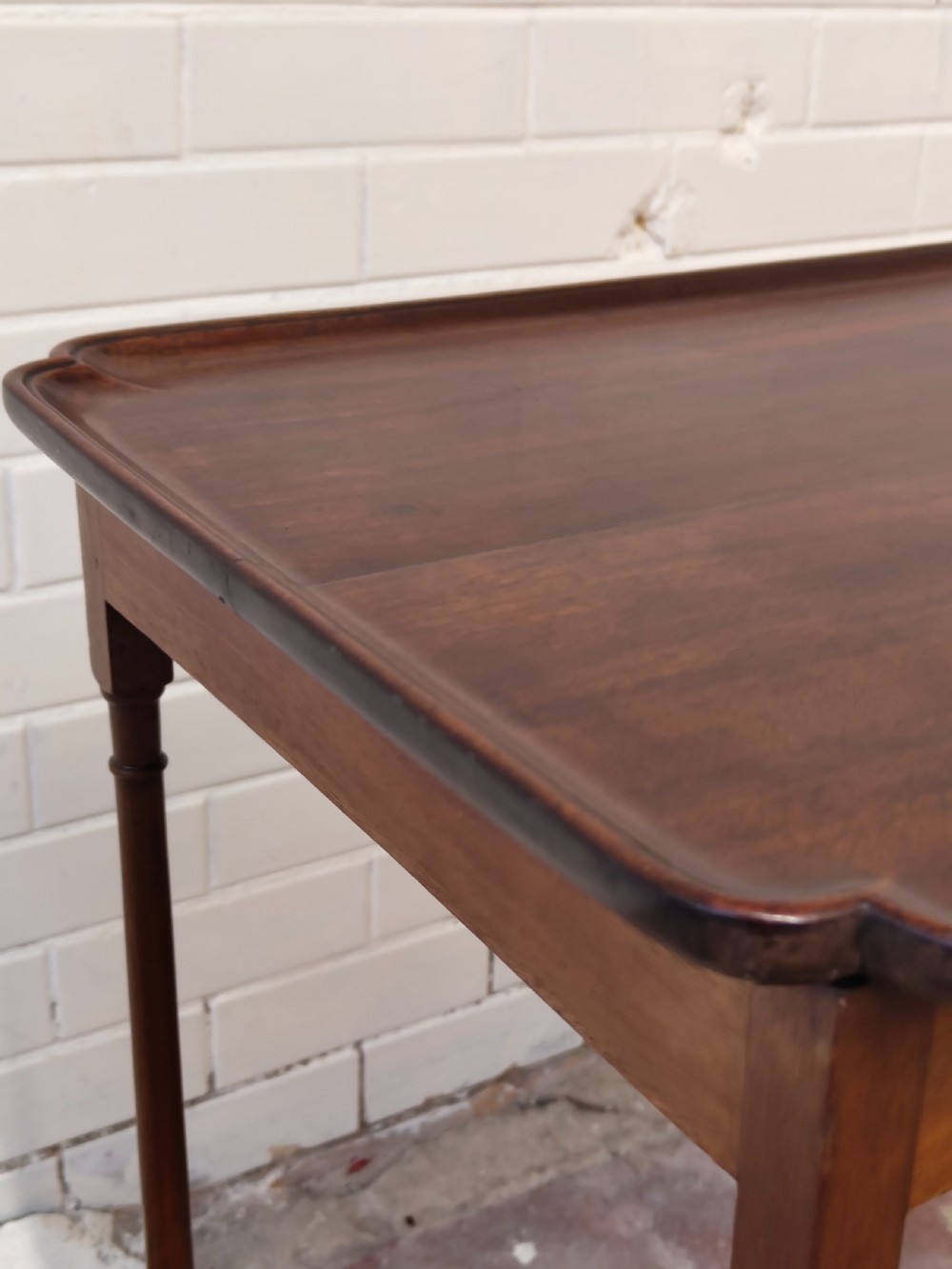 A tall Edwardian mahogany occasional table featuring a tray top with raised edges and slender spider legs connected by lower stretchers. View VII