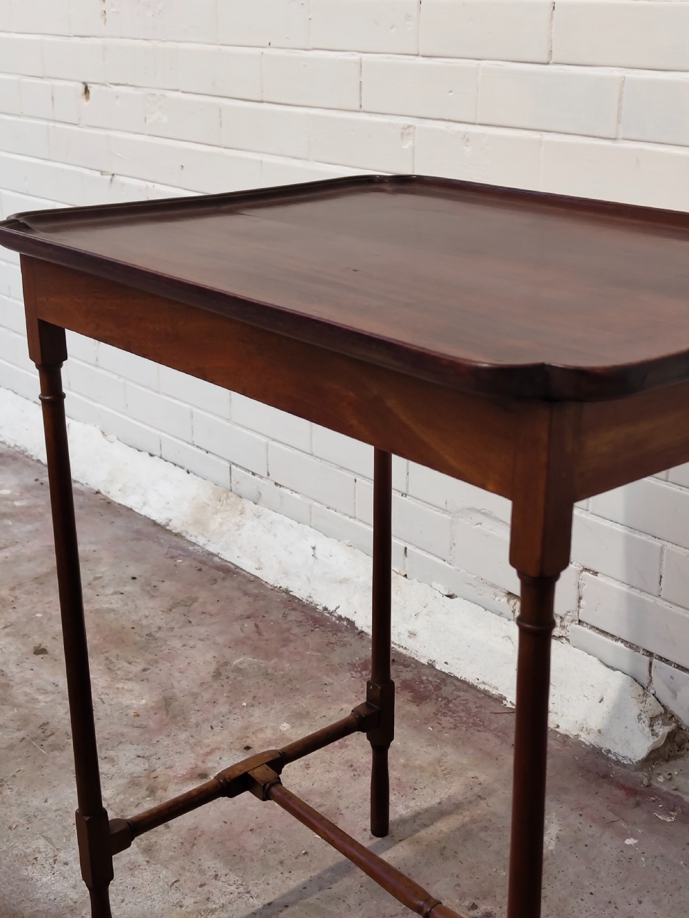 A tall Edwardian mahogany occasional table featuring a tray top with raised edges and slender spider legs connected by lower stretchers. View VIII