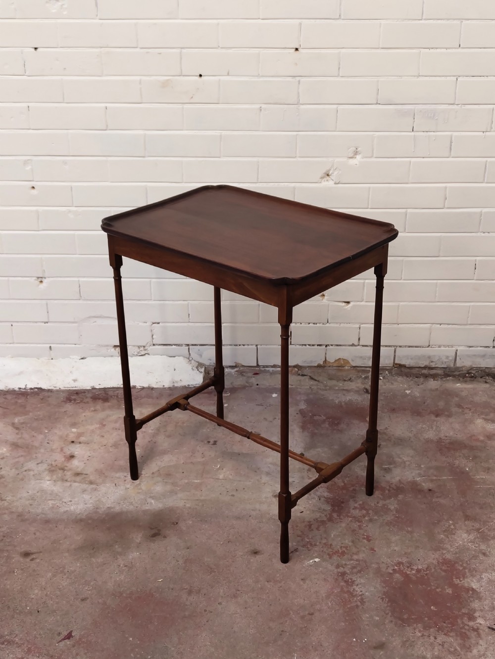 A tall Edwardian mahogany occasional table featuring a tray top with raised edges and slender spider legs connected by lower stretchers. View XVII